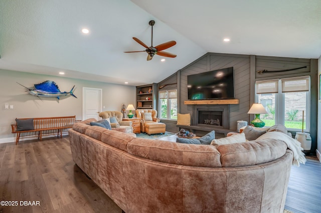 living room with a large fireplace, ceiling fan, lofted ceiling, and wood-type flooring