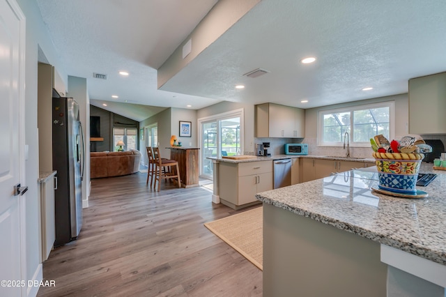 kitchen with sink, cream cabinetry, stainless steel fridge, and light stone countertops