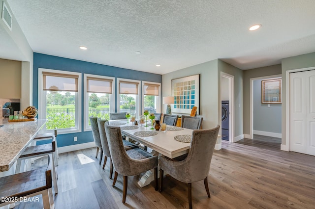 dining space with hardwood / wood-style flooring, plenty of natural light, a textured ceiling, and washer / clothes dryer