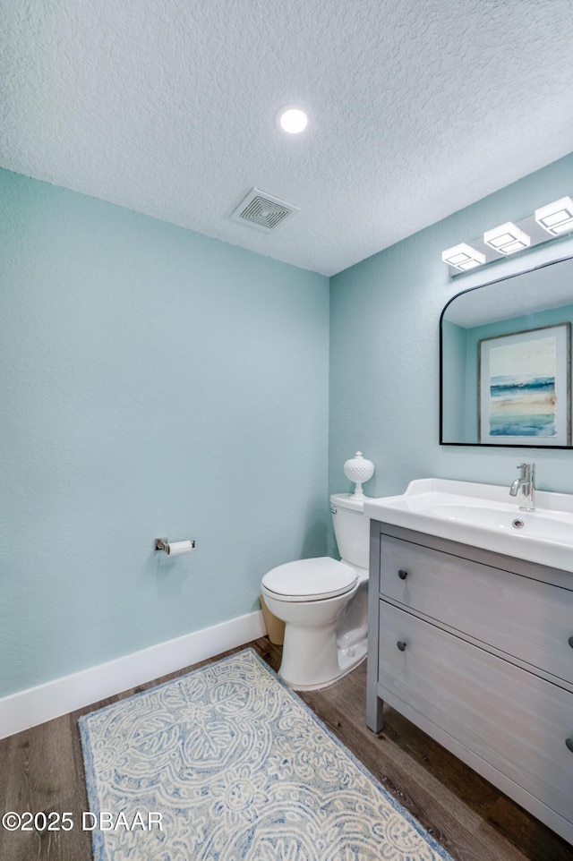 bathroom with hardwood / wood-style floors, a textured ceiling, toilet, and vanity