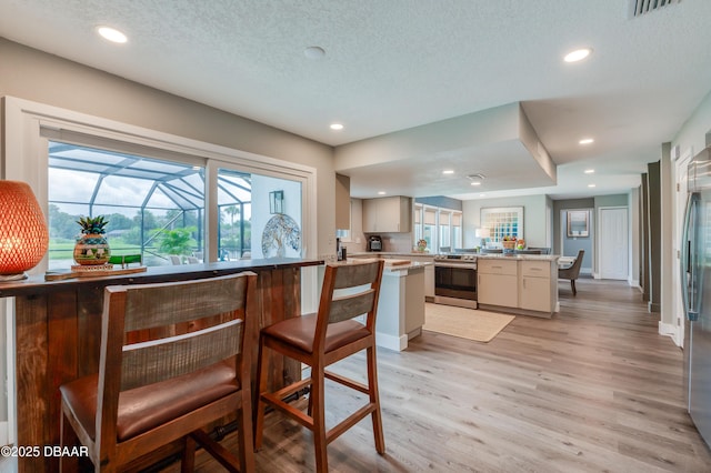 kitchen featuring kitchen peninsula, stainless steel electric stove, plenty of natural light, and light hardwood / wood-style flooring