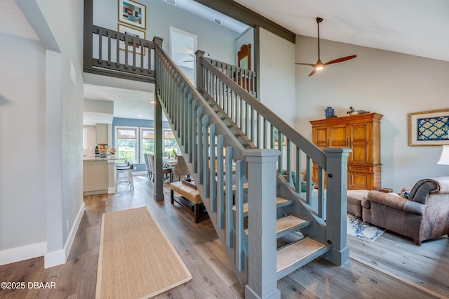 stairway with ceiling fan, wood-type flooring, and high vaulted ceiling