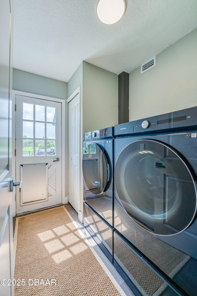 clothes washing area with a textured ceiling and washing machine and dryer