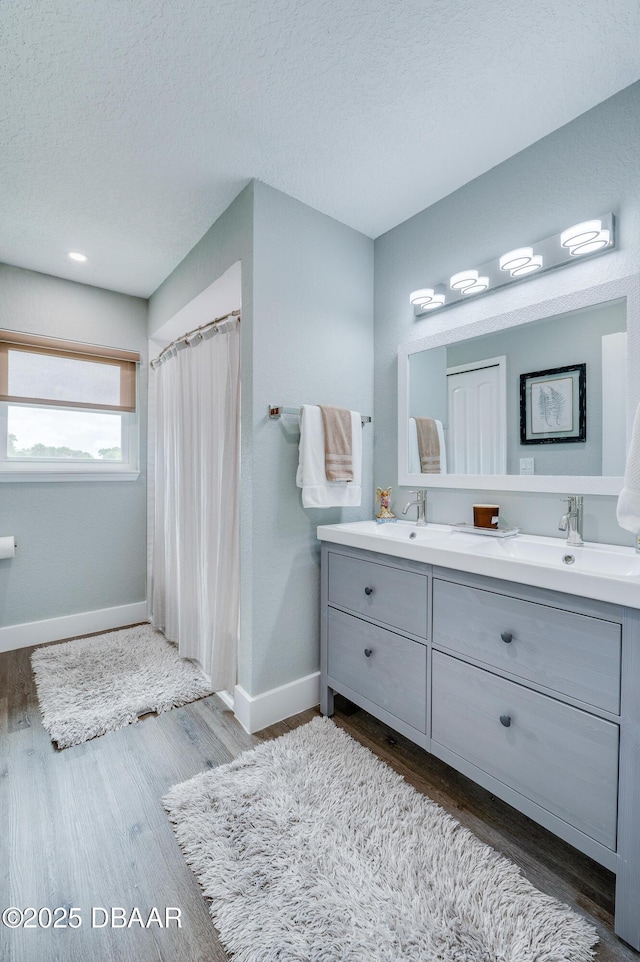 bathroom with wood-type flooring, vanity, and a textured ceiling