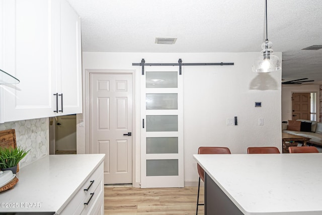 792 N Beach St, Ormond Beach, FL 32174 - kitchen with a kitchen breakfast bar, light wood-style flooring, white cabinetry, pendant lighting, and a barn door