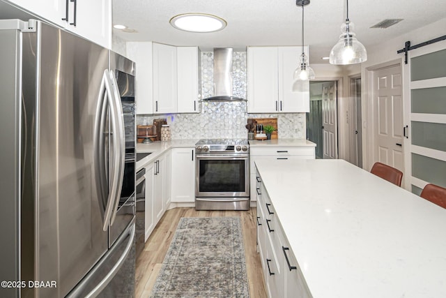 792 N Beach St, Ormond Beach, FL 32174 - kitchen with appliances with stainless steel finishes, wall chimney range hood, light wood finished floors, a barn door, and backsplash
