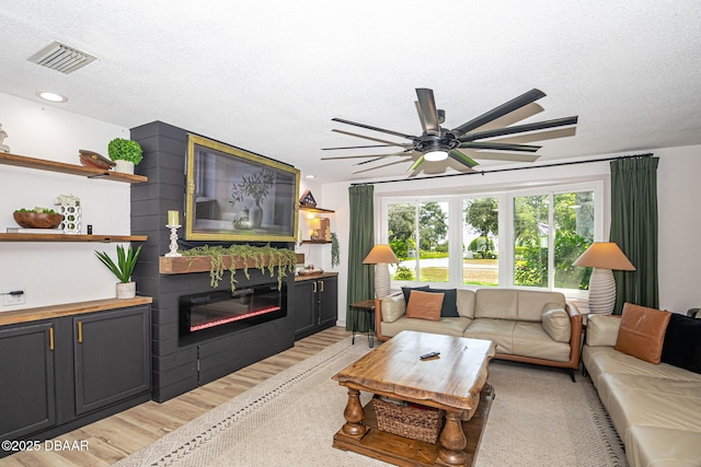 792 N Beach St, Ormond Beach, FL 32174 - living area with a glass covered fireplace, light wood-type flooring, a textured ceiling, and ceiling fan