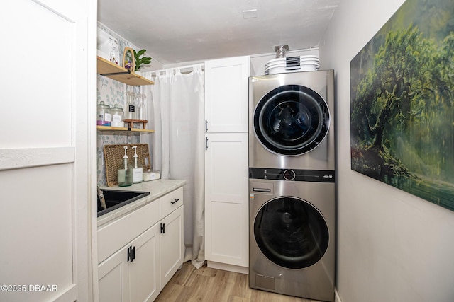 792 N Beach St, Ormond Beach, FL 32174 - laundry area featuring stacked washer and clothes dryer, cabinet space, and light wood-style flooring
