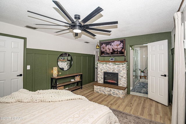 792 N Beach St, Ormond Beach, FL 32174 - bedroom featuring wood finished floors, a fireplace, a textured ceiling, ceiling fan, and a decorative wall