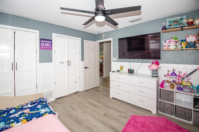792 N Beach St, Ormond Beach, FL 32174 - bedroom featuring light wood finished floors, a wainscoted wall, ceiling fan, multiple closets, and a textured wall