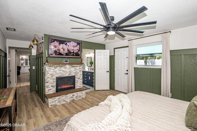 792 N Beach St, Ormond Beach, FL 32174 - bedroom with wood finished floors, a stone fireplace, a textured ceiling, ceiling fan, and ensuite bathroom