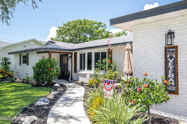 792 N Beach St, Ormond Beach, FL 32174 - doorway to property featuring brick siding, a yard, and roof with shingles