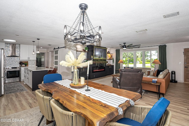 792 N Beach St, Ormond Beach, FL 32174 - dining space with a glass covered fireplace, a barn door, a ceiling fan, light wood finished floors, and a textured ceiling