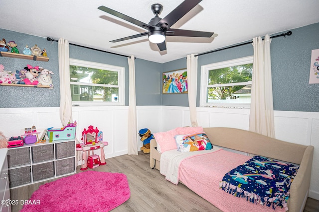 792 N Beach St, Ormond Beach, FL 32174 - bedroom with wood finished floors, wainscoting, a ceiling fan, a decorative wall, and a textured wall