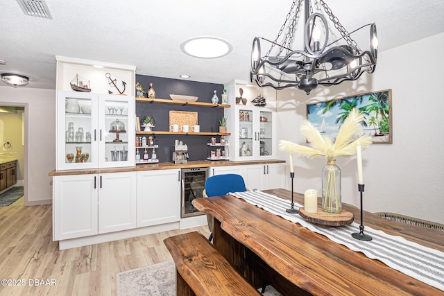 792 N Beach St, Ormond Beach, FL 32174 - dining space with beverage cooler, a chandelier, light wood-type flooring, a dry bar, and a textured ceiling