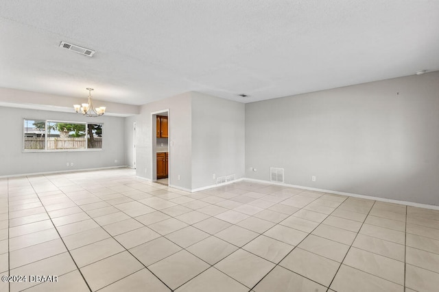 spare room with light tile patterned flooring and an inviting chandelier