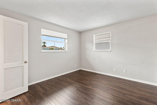 unfurnished room with dark hardwood / wood-style flooring and a textured ceiling