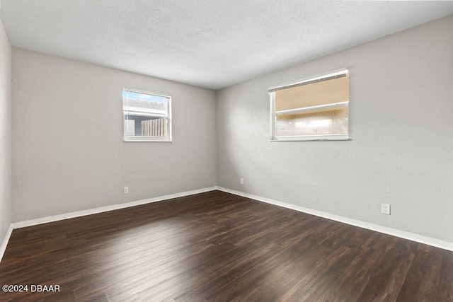 unfurnished room with dark hardwood / wood-style flooring and a textured ceiling