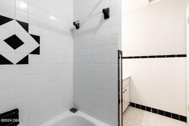 bathroom with vanity, tiled shower / bath, and tile walls