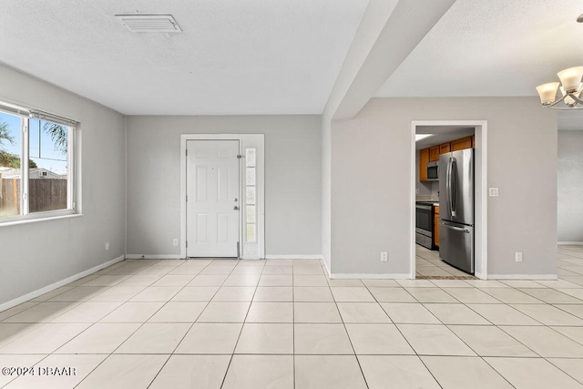 unfurnished room featuring a chandelier, light tile patterned floors, and beam ceiling