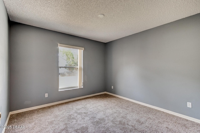 empty room featuring a textured ceiling, carpet, and baseboards