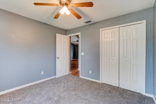 unfurnished bedroom featuring a textured ceiling, visible vents, a closet, baseboards, and carpet floors