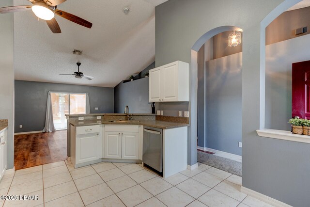 kitchen with stainless steel dishwasher, white cabinets, a sink, a ceiling fan, and a peninsula