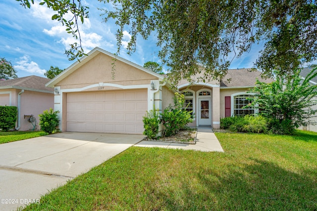 ranch-style house featuring a garage and a front lawn