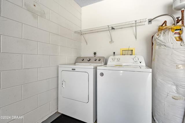 washroom with washer and clothes dryer, concrete block wall, and laundry area