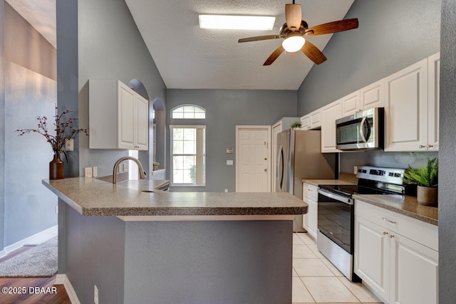 kitchen with lofted ceiling, white cabinetry, ceiling fan, stainless steel appliances, and a peninsula