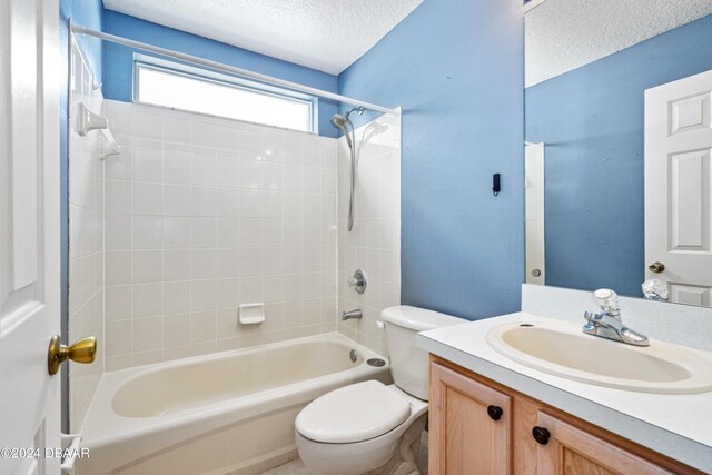 full bathroom with toilet, vanity, tiled shower / bath, and a textured ceiling