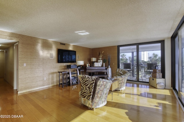 living room featuring expansive windows, light hardwood / wood-style floors, and a textured ceiling