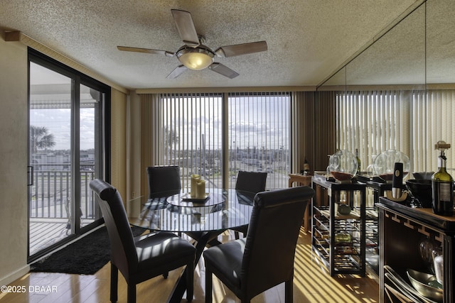 dining area with hardwood / wood-style flooring, a textured ceiling, floor to ceiling windows, and ceiling fan