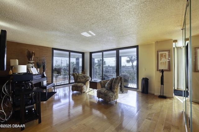 living room featuring a wall of windows, light hardwood / wood-style floors, and a textured ceiling