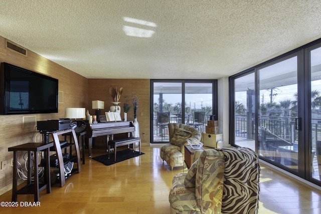 living room featuring expansive windows, light hardwood / wood-style floors, and a textured ceiling