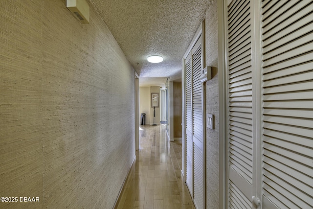 hallway featuring light hardwood / wood-style floors and a textured ceiling