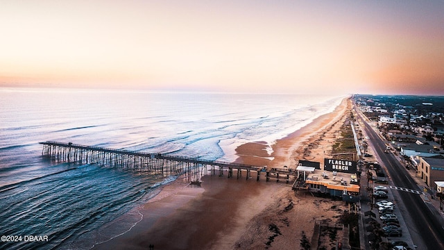 aerial view at dusk with a water view and a beach view