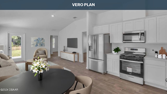 kitchen with white cabinets, appliances with stainless steel finishes, light hardwood / wood-style floors, and lofted ceiling