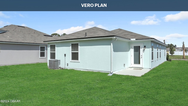 rear view of house with central AC unit and a lawn