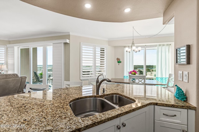 3737 S Atlantic Ave Unit 504, Daytona Beach Shores, FL 32118 - kitchen with a sink, light stone countertops, crown molding, a chandelier, and white cabinetry