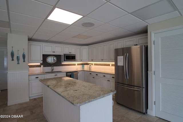 3606 S Peninsula Dr Unit 608, Port Orange, FL 32127 - kitchen with stainless steel appliances, a center island, white cabinetry, a drop ceiling, and a wainscoted wall