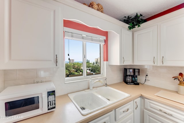 3606 S Peninsula Dr Unit 608, Port Orange, FL 32127 - kitchen featuring white microwave, white cabinetry, decorative backsplash, and light countertops