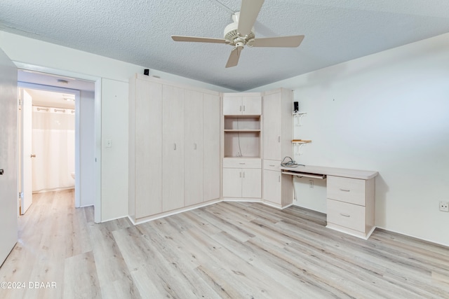 unfurnished office with a textured ceiling, light wood-type flooring, and ceiling fan