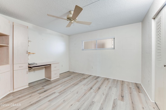 3606 S Peninsula Dr Unit 608, Port Orange, FL 32127 - unfurnished bedroom featuring light wood-style floors, a textured ceiling, a desk, ceiling fan, and a closet