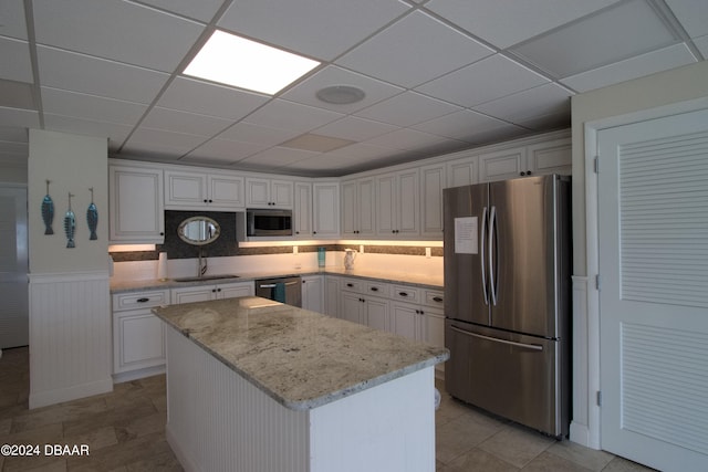 kitchen featuring white cabinetry, stainless steel appliances, light stone counters, and a kitchen island