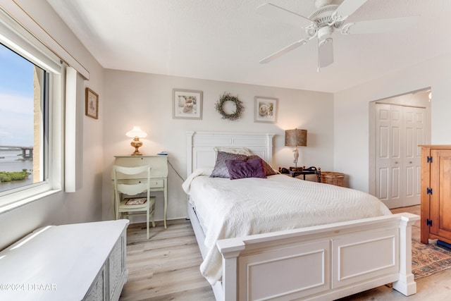 bedroom with light hardwood / wood-style flooring, ceiling fan, and a closet