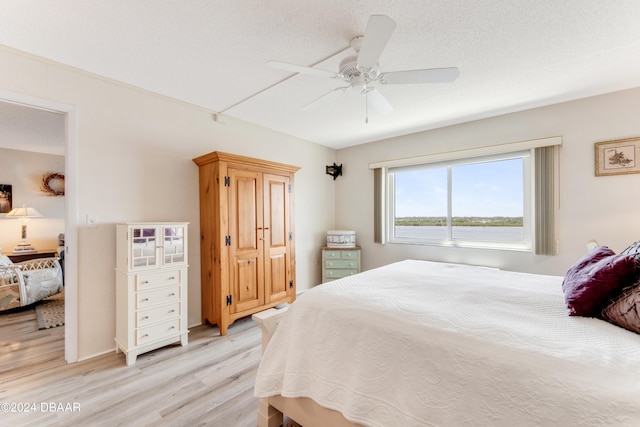 bedroom featuring ceiling fan, a textured ceiling, and light hardwood / wood-style floors