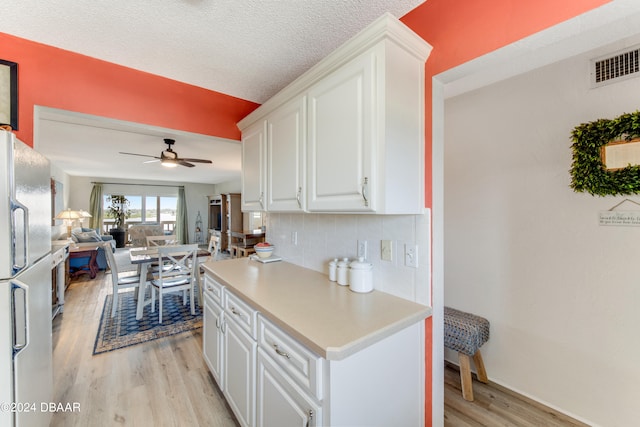 kitchen with white cabinets, light hardwood / wood-style floors, ceiling fan, and white refrigerator