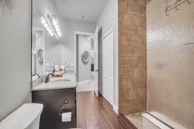 bathroom with vanity, toilet, and a tile shower