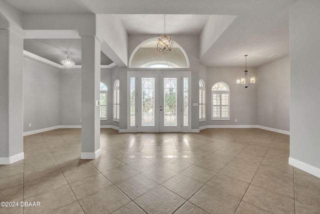 foyer entrance with light tile patterned flooring, an inviting chandelier, and french doors